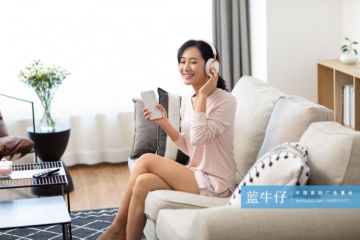 快乐年轻女士在家戴着耳机听音乐