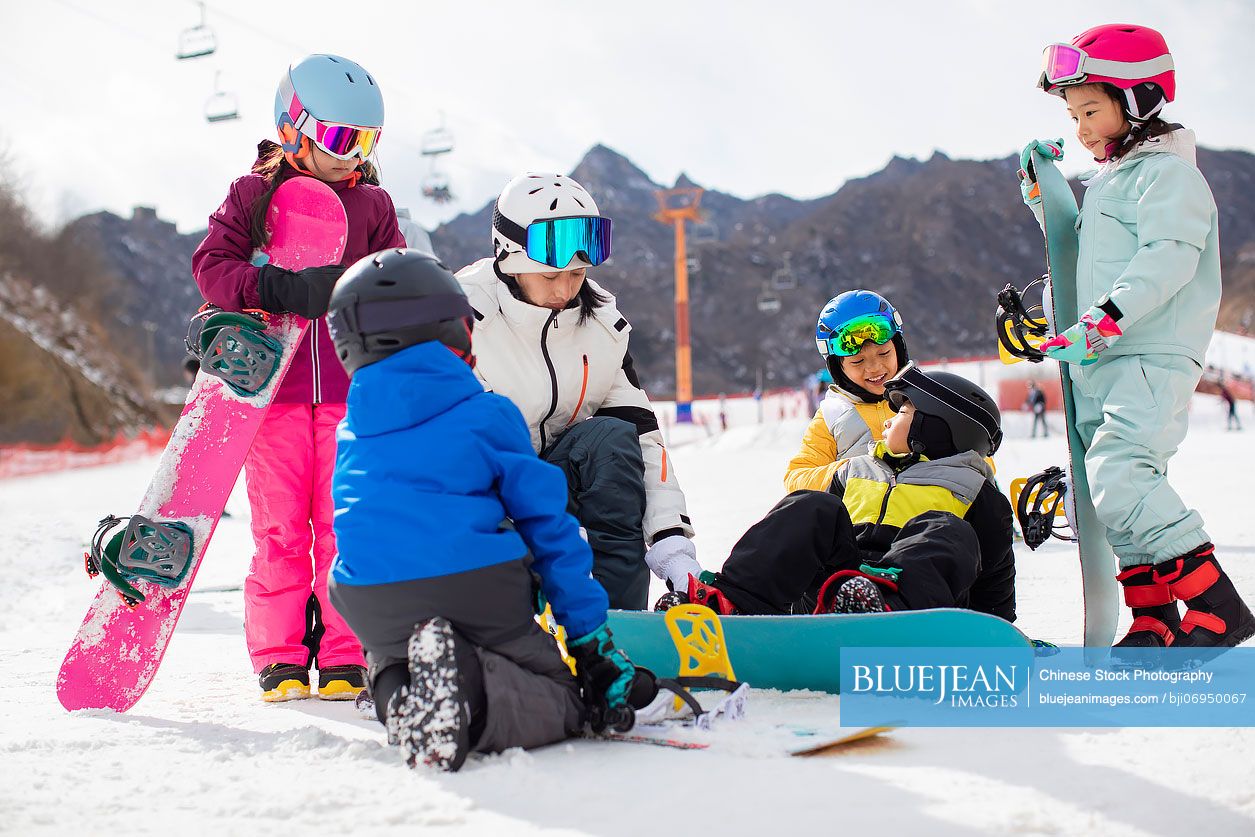 Chinese children learning how to snowboard with their coach