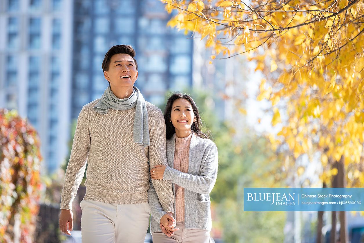 Happy young Chinese couple strolling together in autumn