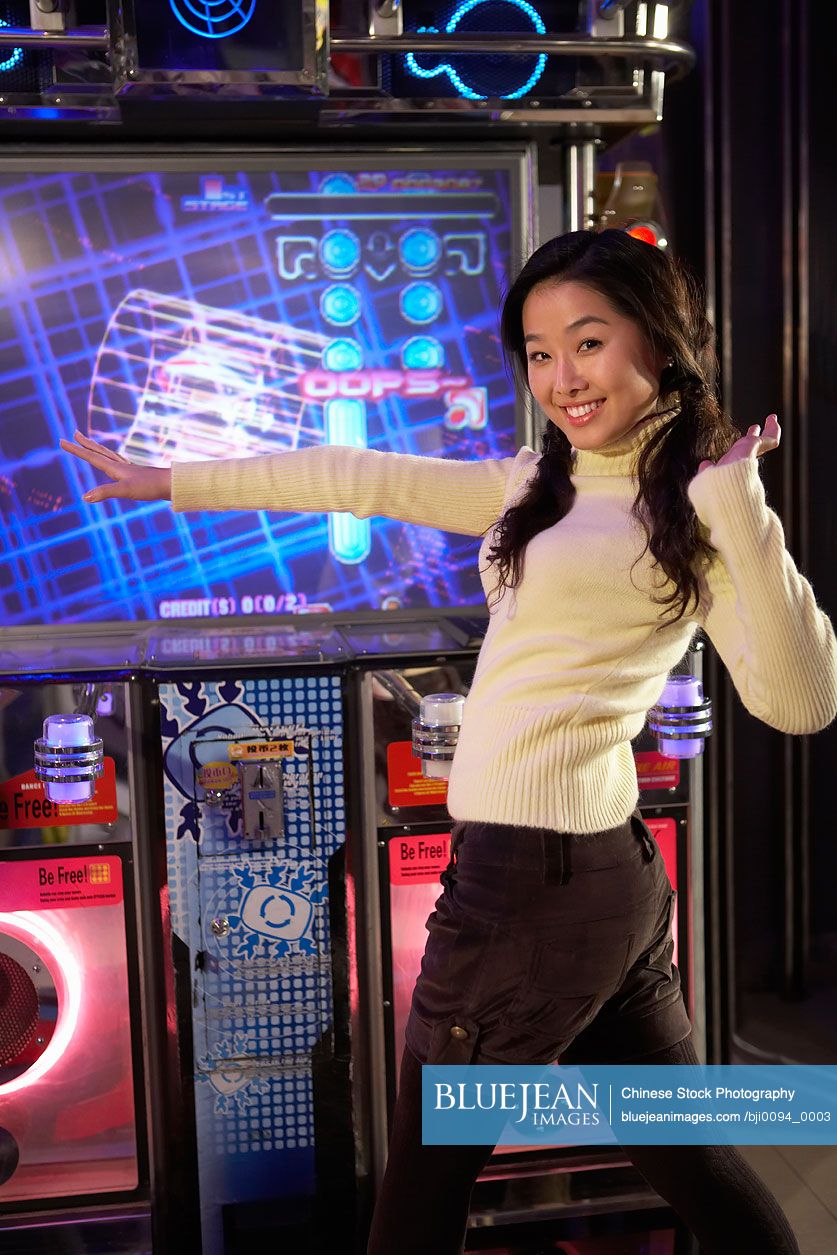 Chinese teenage girl on dancing game at arcade