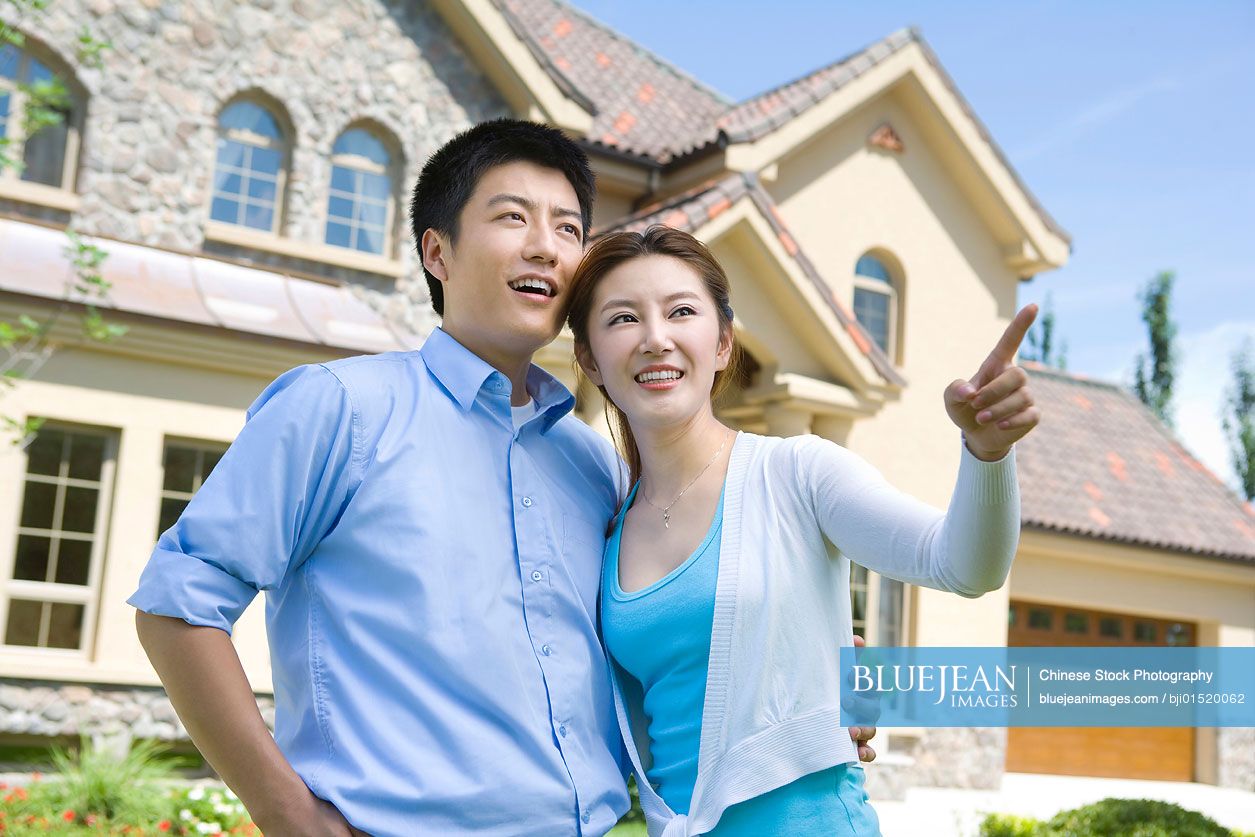 Young Chinese couple in front of house