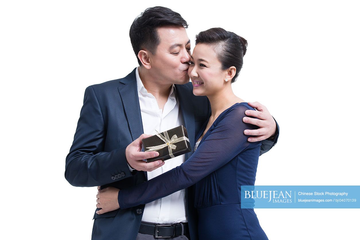 Chinese husband kissing wife with gift in hand