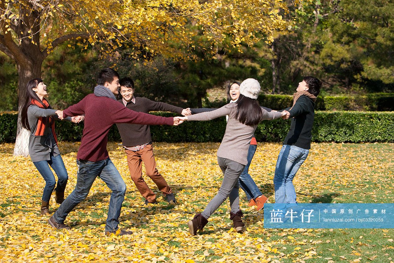 秋天年轻人在草地上手拉手转圈
