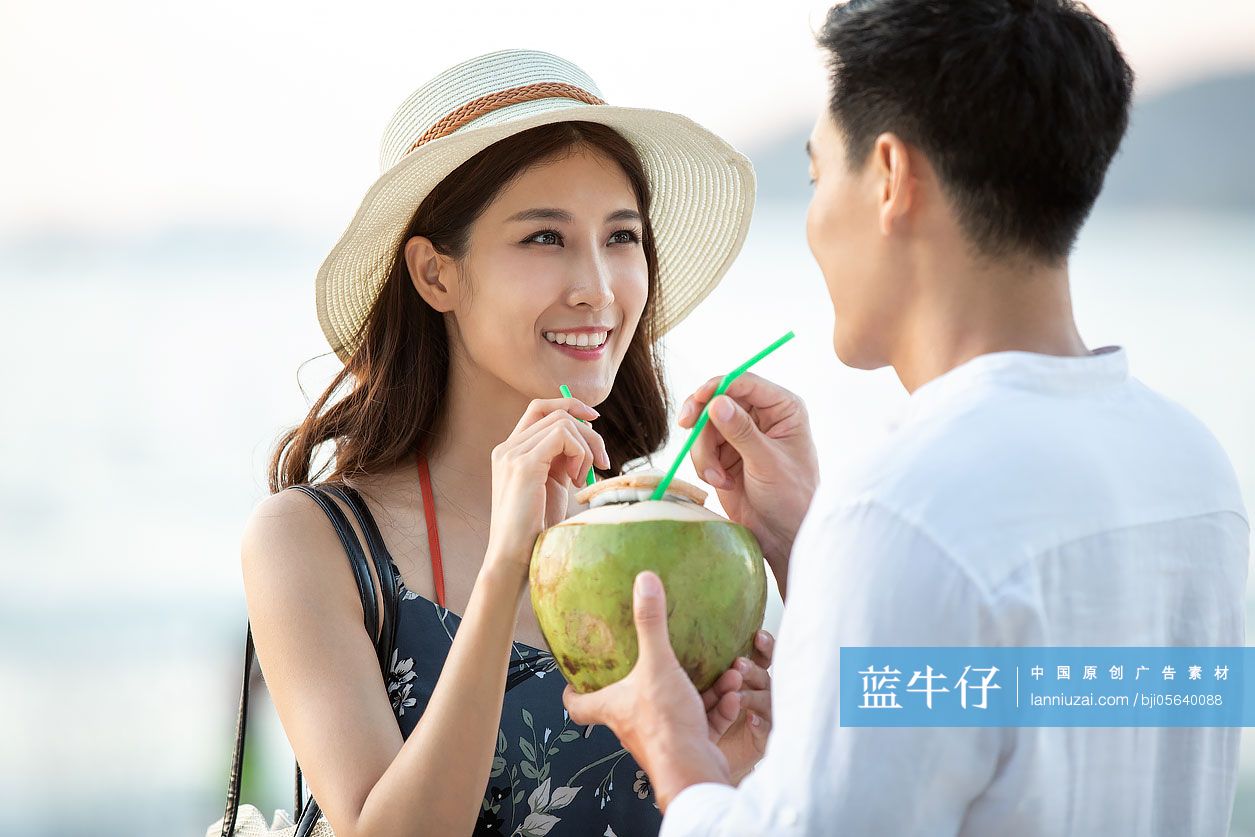 快乐的年轻情侣在沙滩喝椰汁