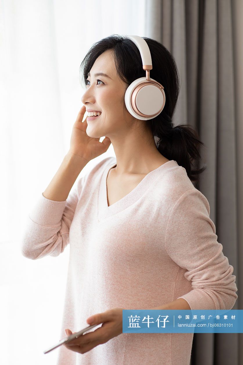 快乐年轻女士在家戴着耳机听音乐