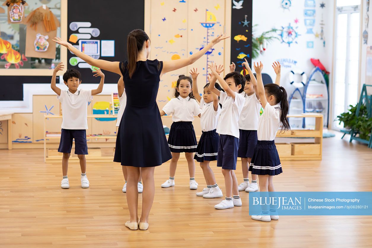 Chinese teacher teaching children dancing in classroom
