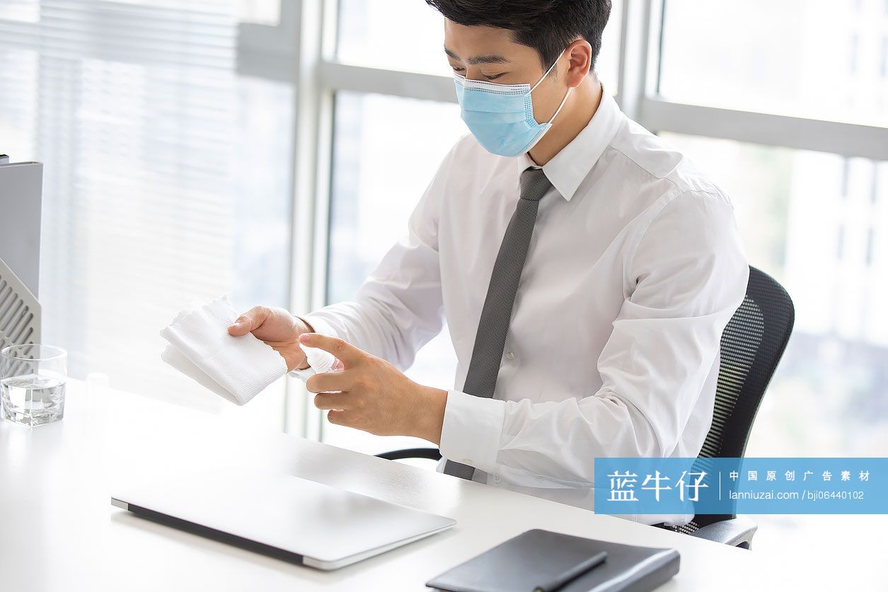 年轻的商务男士在办公室使用消毒液杀菌消毒