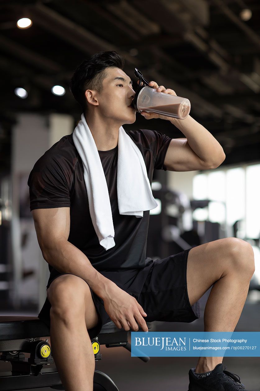 Young Chinese man taking a break from workout at gym