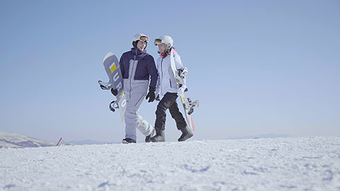 Young Chinese couple walking with snowboards on the snow,4K