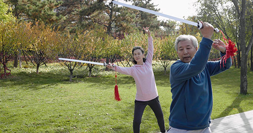 Cheerful senior Chinese adult practicing swords in the park,4K