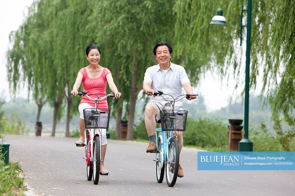 Senior Chinese couple cycling in park