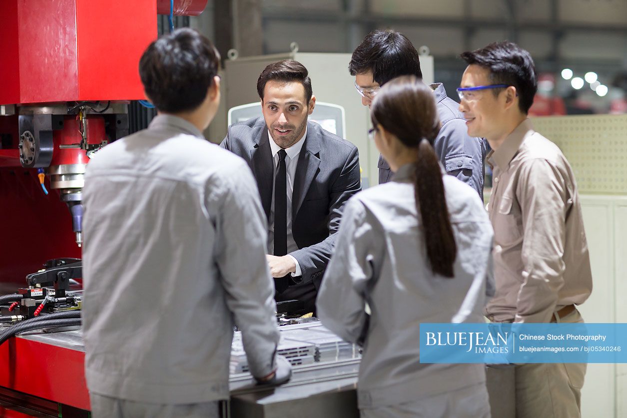 Businessman and engineers checking machine in the factory