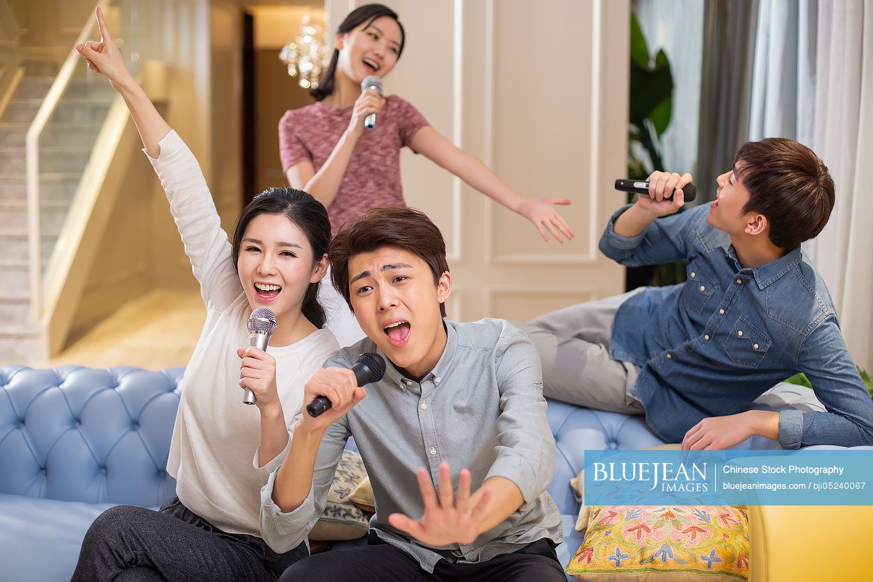 Young Chinese friends singing karaoke at home