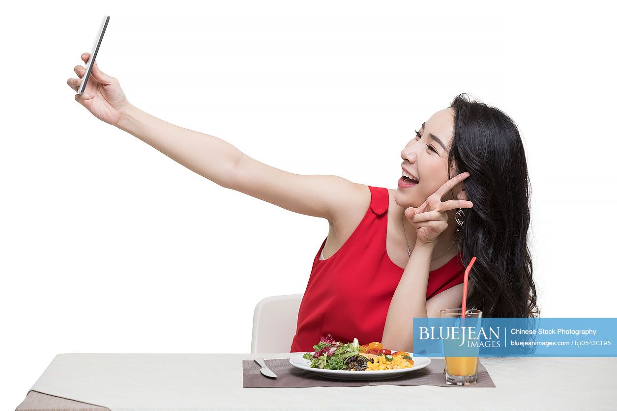 Fashionable young Chinese woman taking self portrait with smart phone