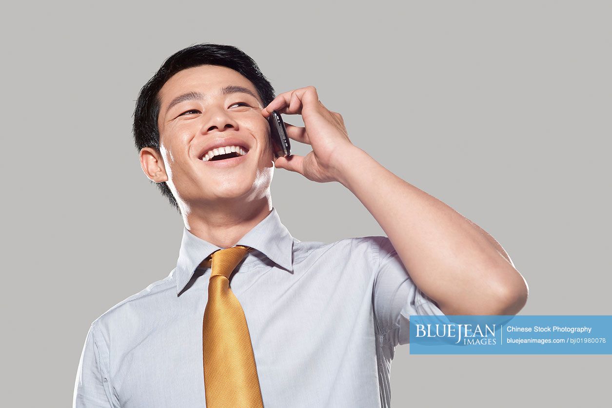 Chinese businessman talking on mobile phone, white background