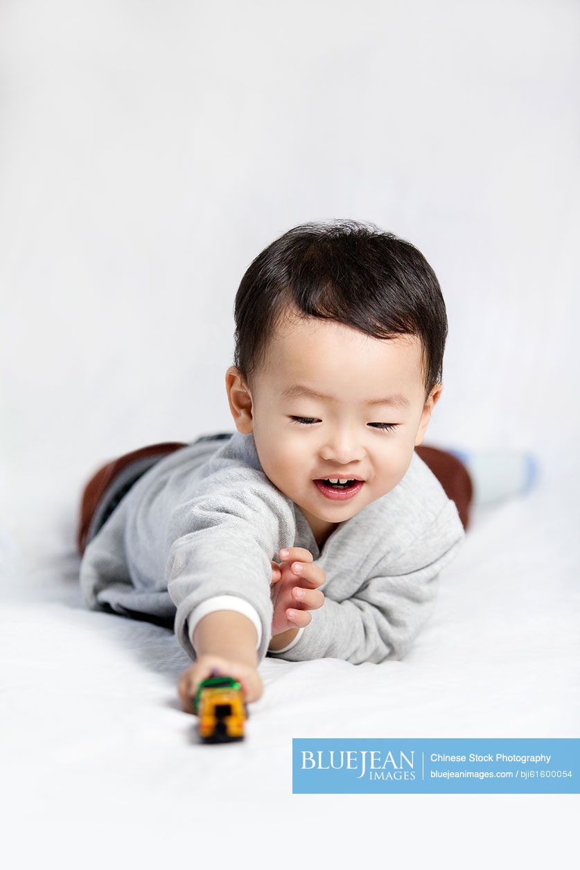 Happy little Chinese boy playing toy car