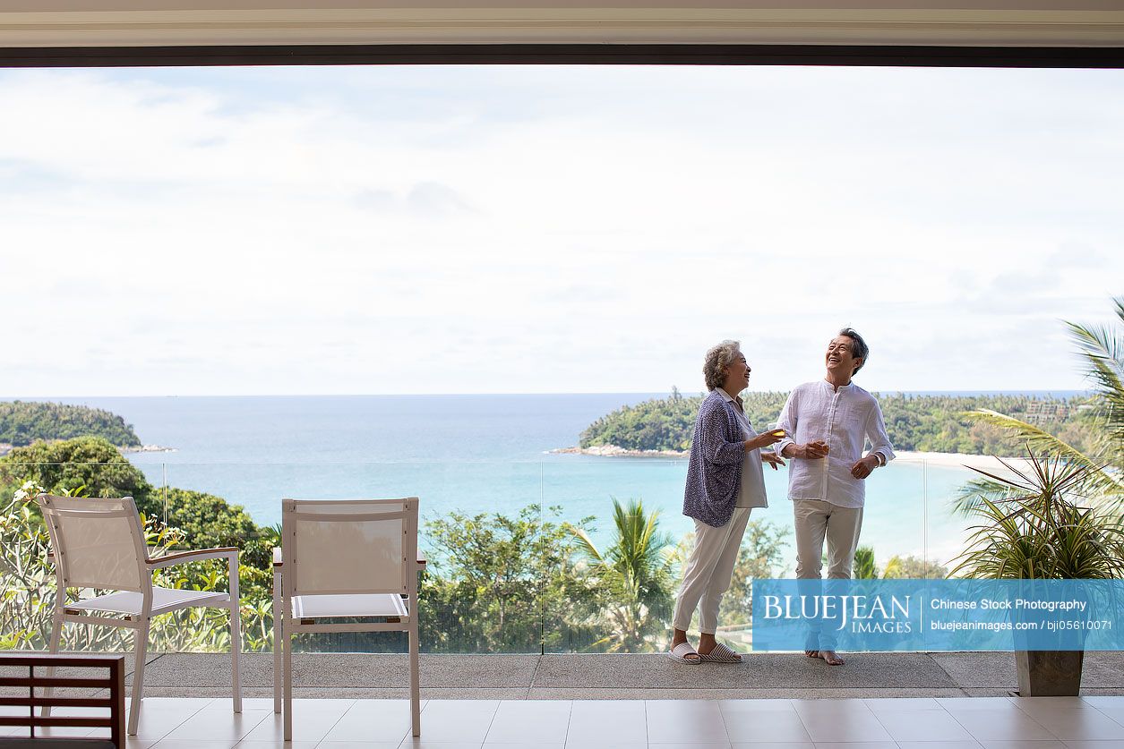 Happy senior Chinese couple relaxing on balcony