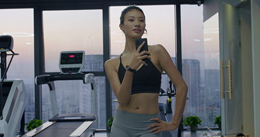 Young Chinese woman taking selfie with smartphone at gym,4K