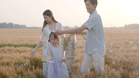 Happy young Chinese family blowing bubbles in wheat field,HD