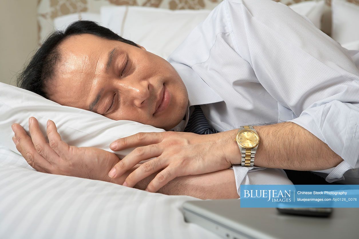 Chinese businessman sleeping next to mobile phone and laptop