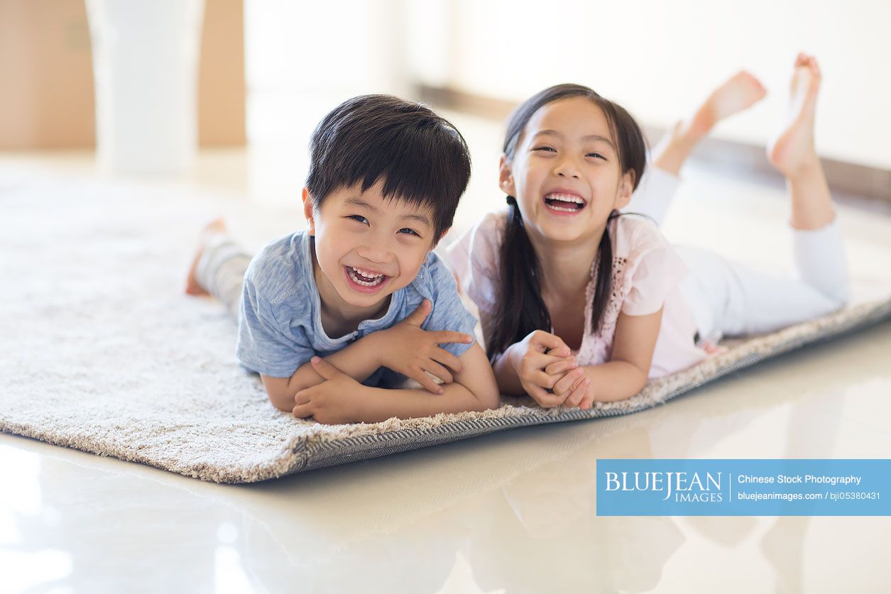 Cute Chinese children lying on carpet in new house