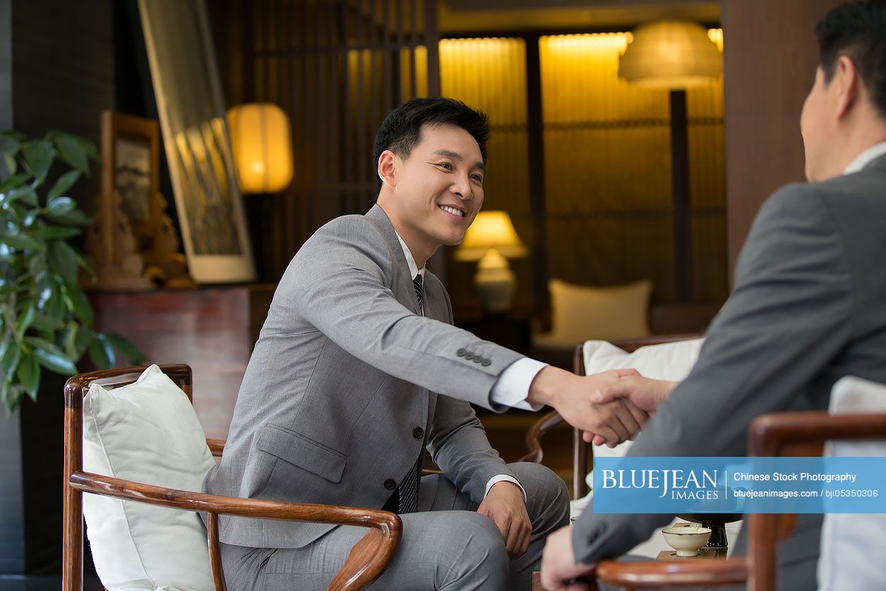 Cheerful Chinese businessmen shaking hands