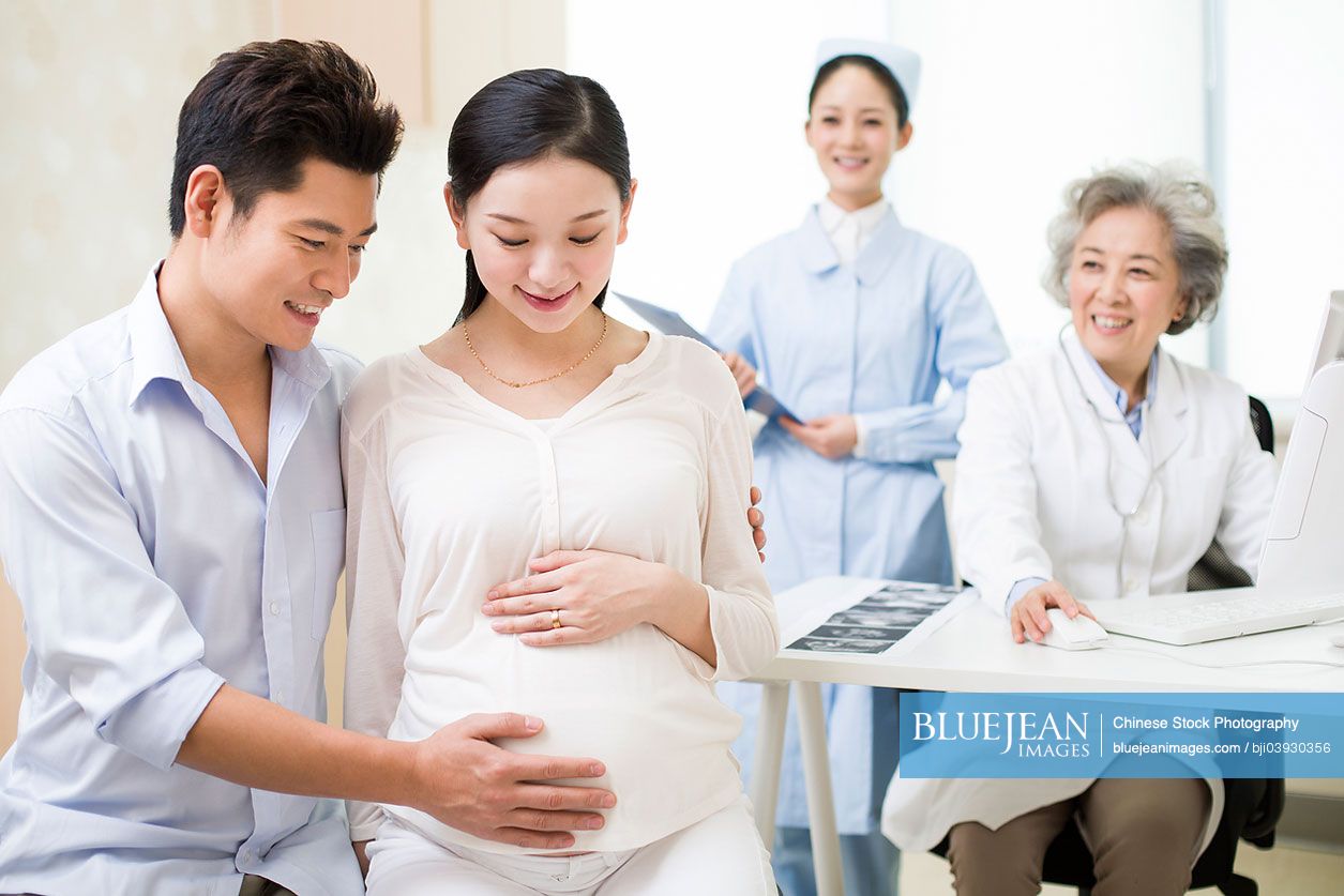 Pregnant Chinese woman and husband in doctor's officeHighres stock
