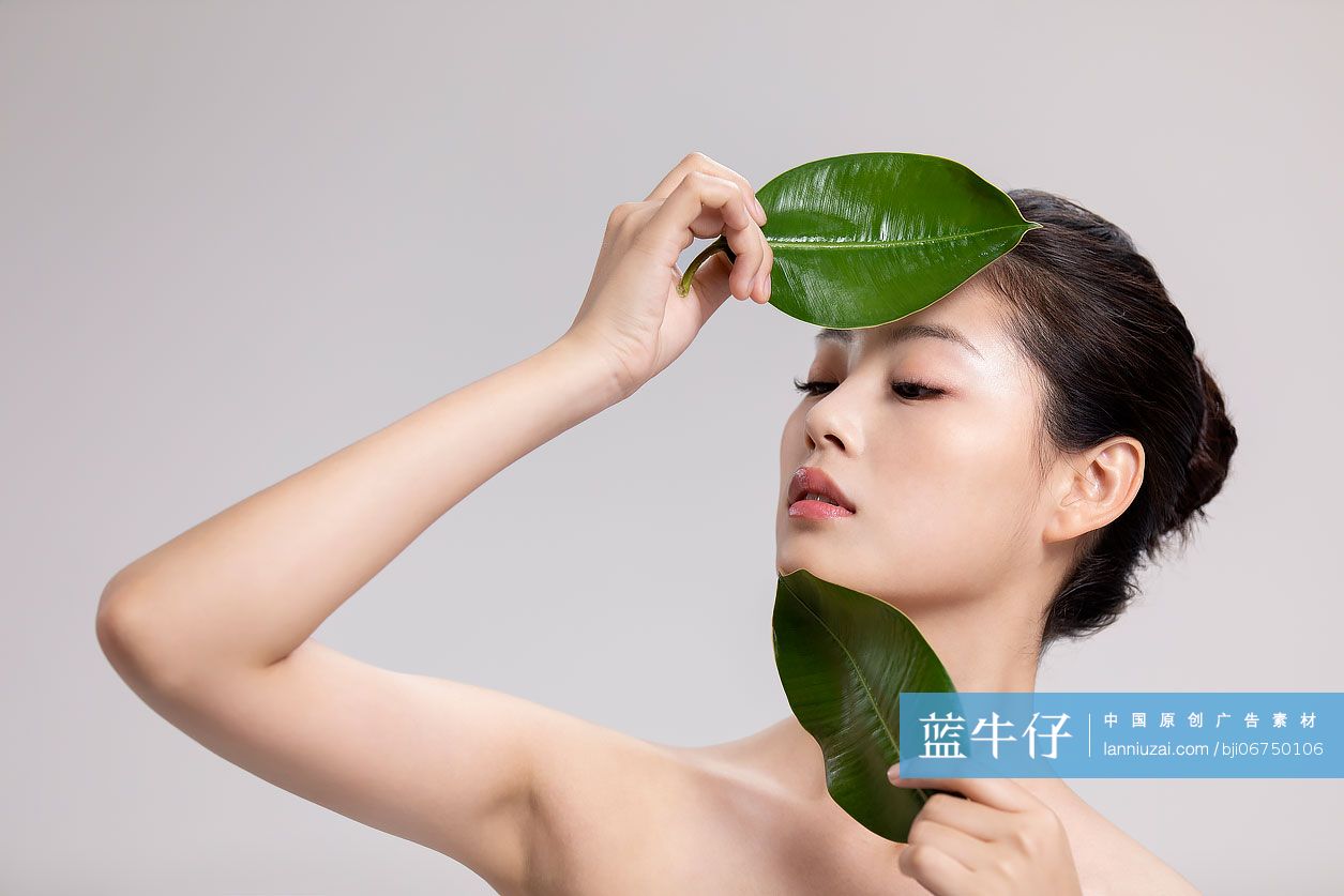 漂亮的年轻女子拿着两片绿叶