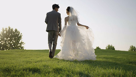 新郎和新娘在草地上牵手走路