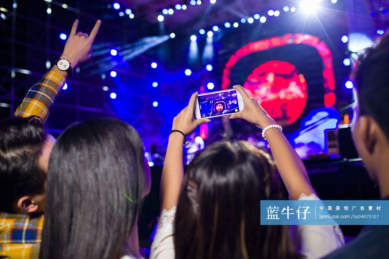 年轻女子在音乐节上用手机拍照