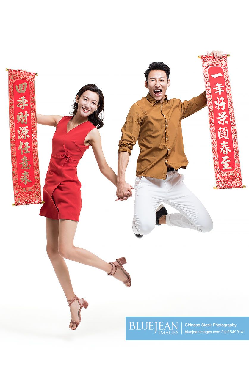 Cheerful young couple with couplets celebrating Chinese new year