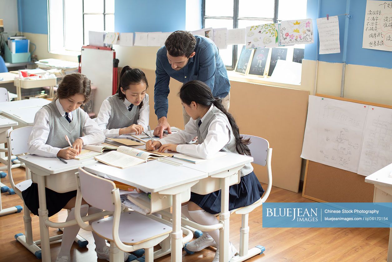 Young teacher helping students in classroom