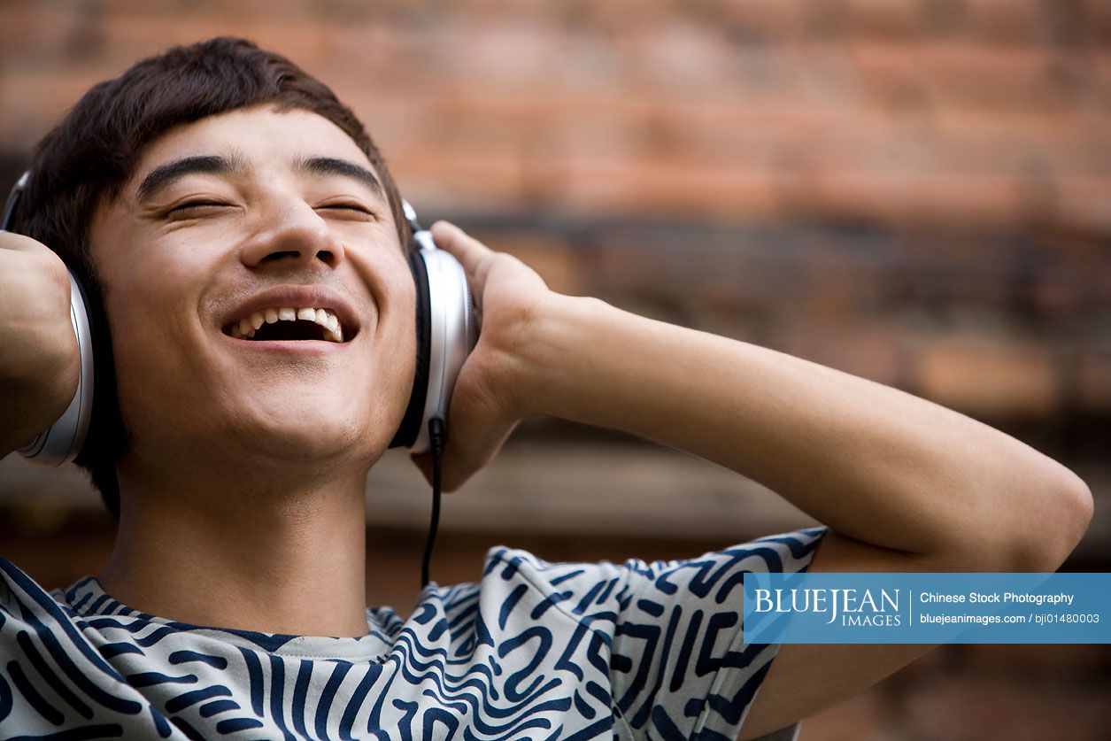 Young Chinese man listening to music on headphones