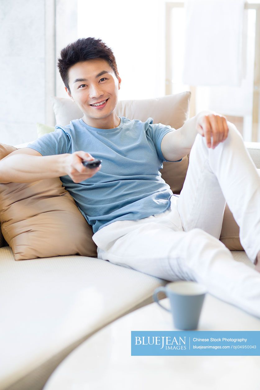 Young Chinese man watching TV at home