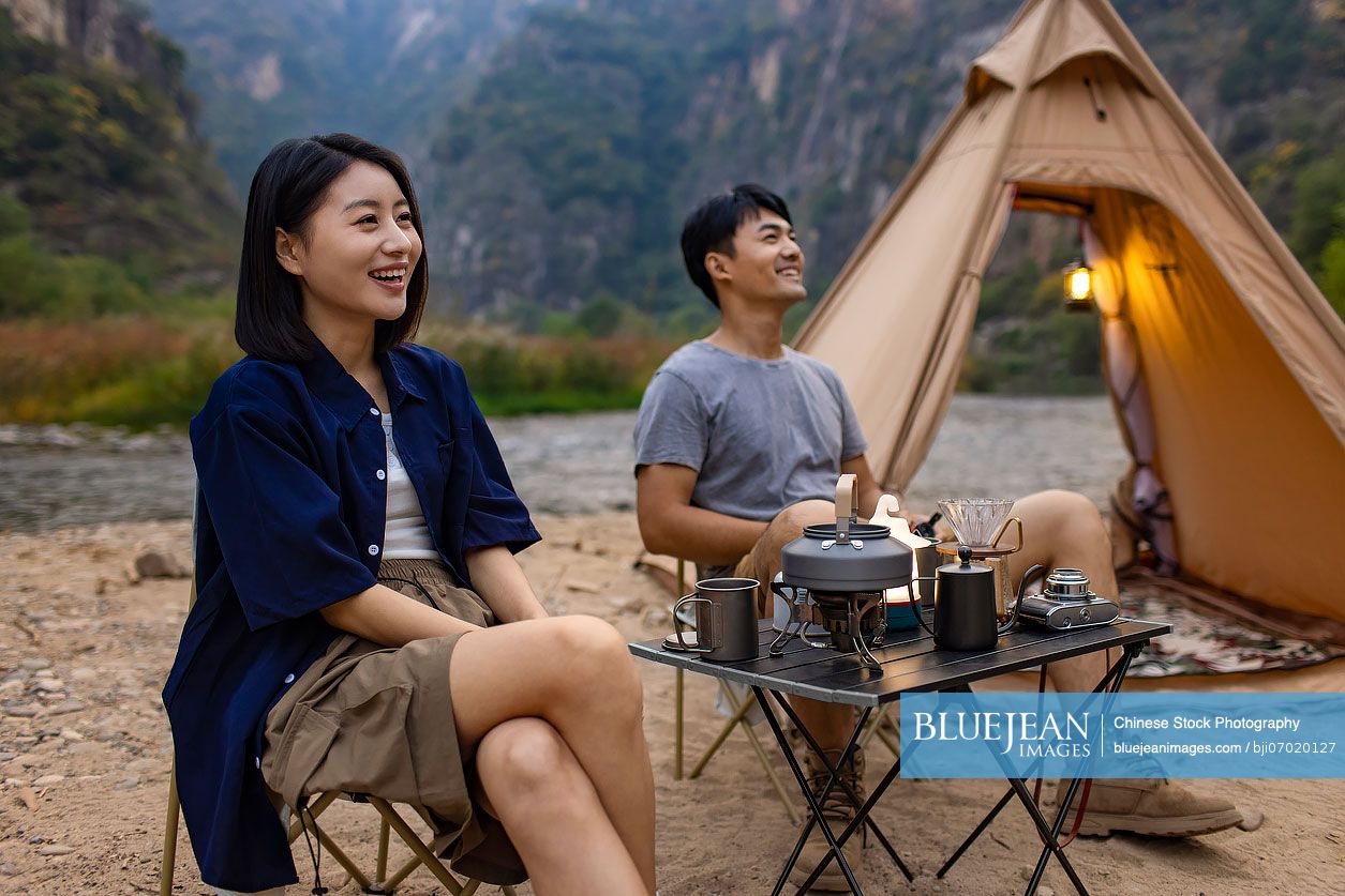 Happy young Chinese couple camping outdoors