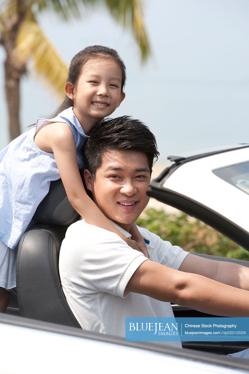 Chinese father and daughter driving in a convertible