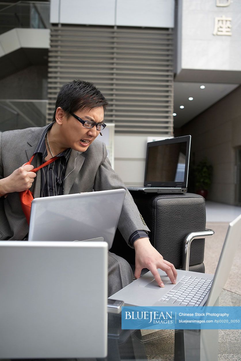 Frustrated Chinese businessman sitting at laptop-High-res stock photo ...