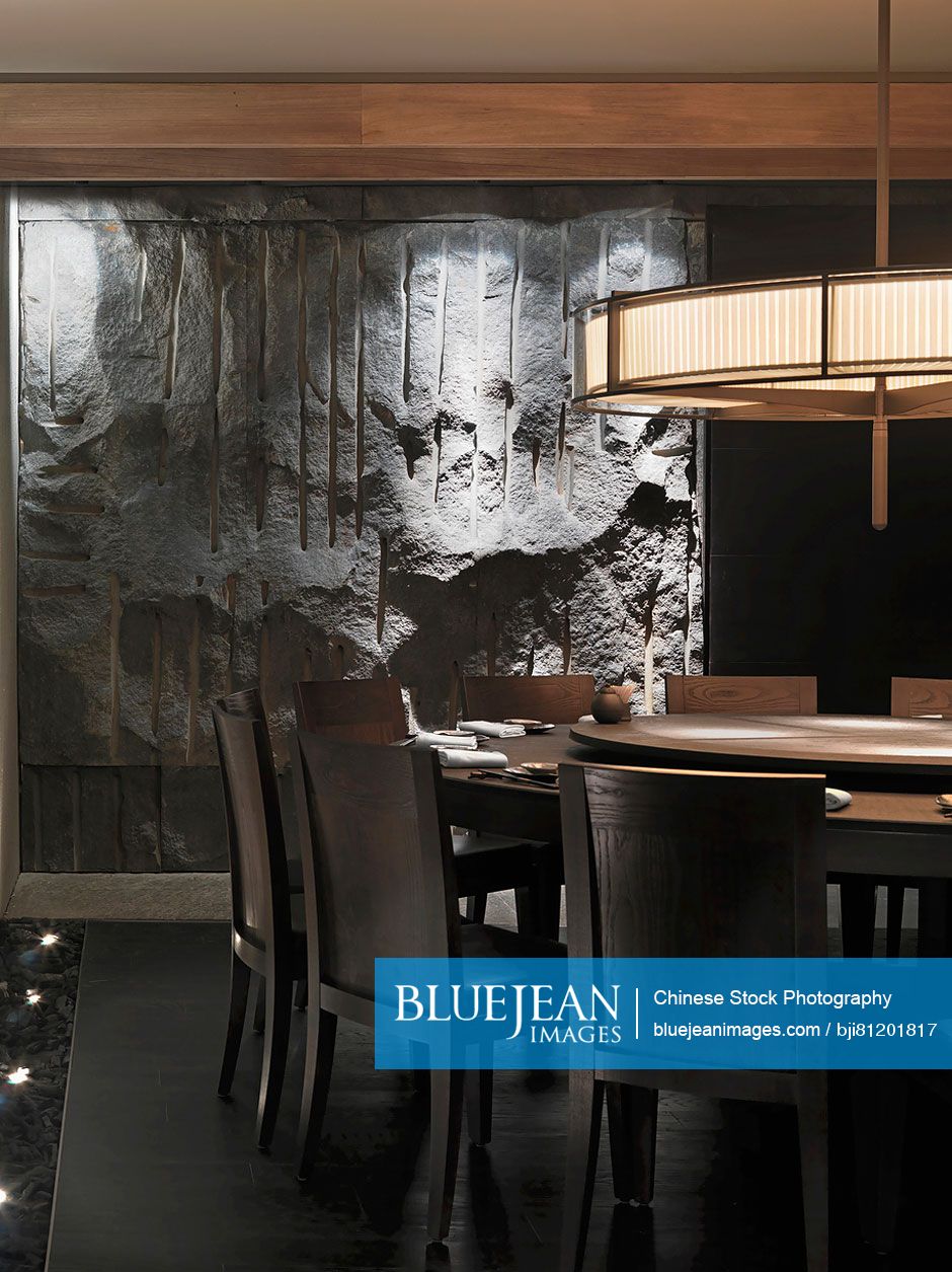 Circular wooden dining table below light fixture in restaurant