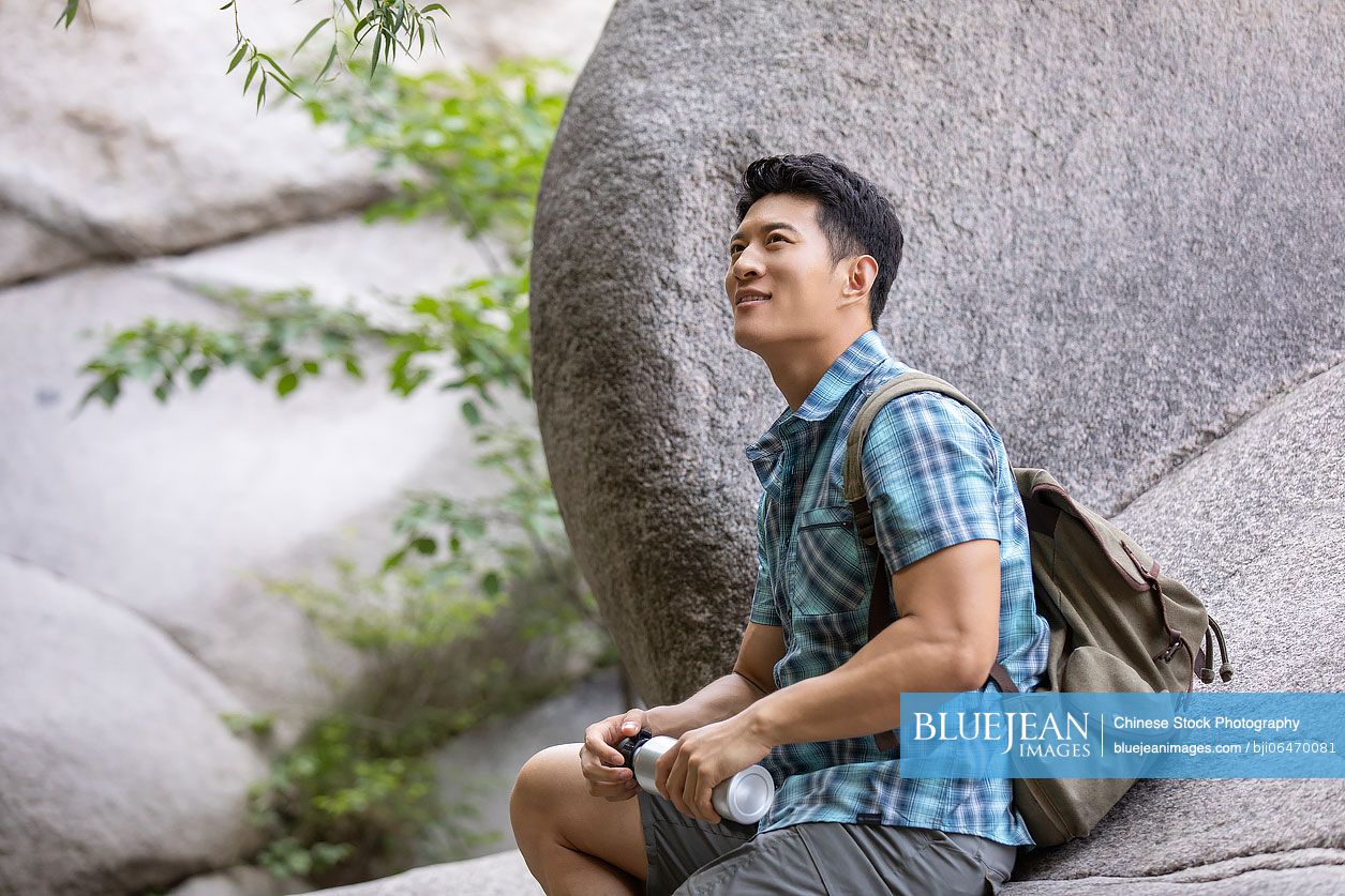 Young Chinese man hiking outdoors