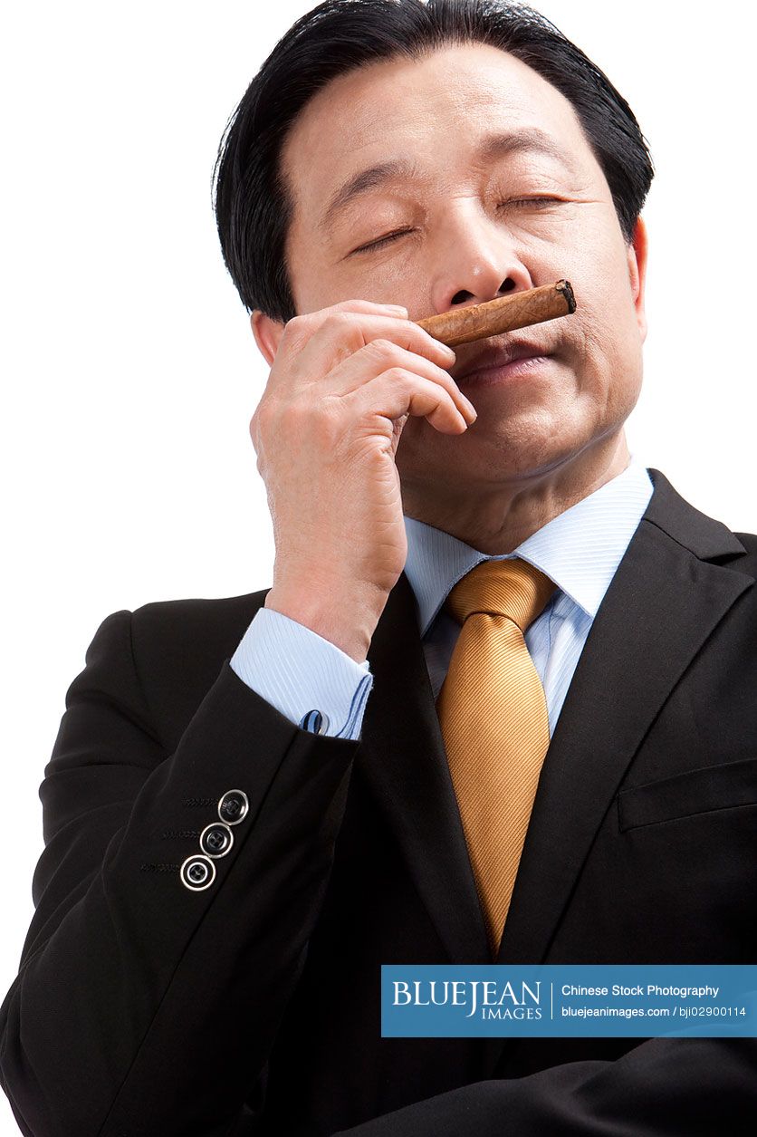 Senior Chinese businessman enjoying a cigar