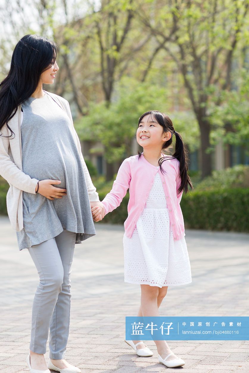 怀有身孕的妈妈和女儿手牵手散步