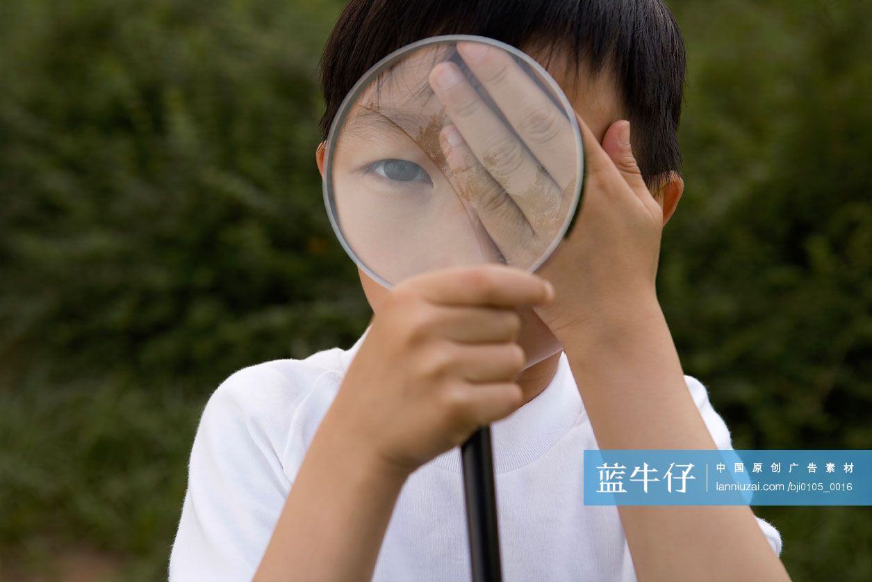 小男孩拿放大镜观察
