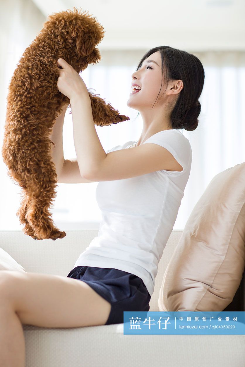 年轻女子和宠物狗在家嬉戏