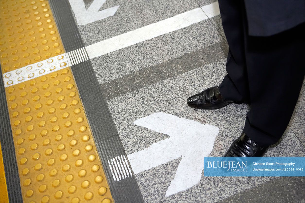 Shot of Chinese businessman's feet waiting on a subway platform