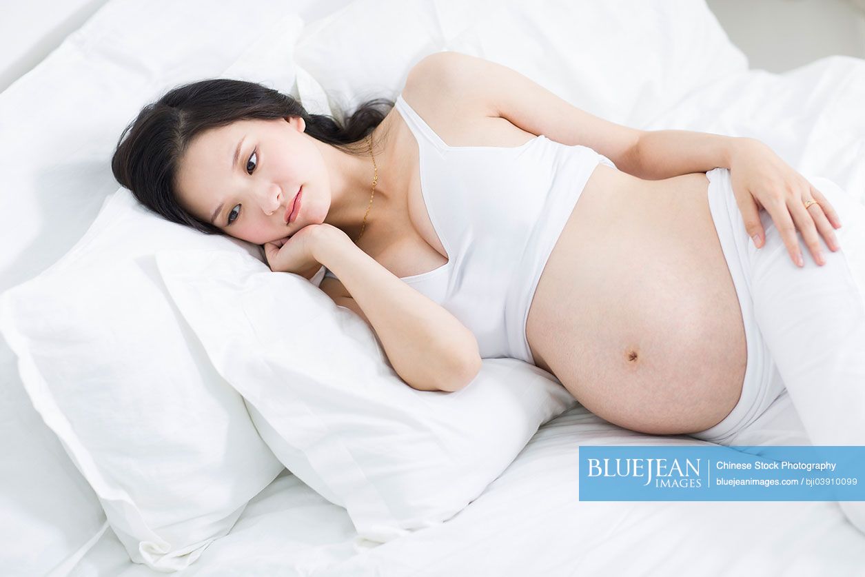 Pregnant Chinese woman lying in bed