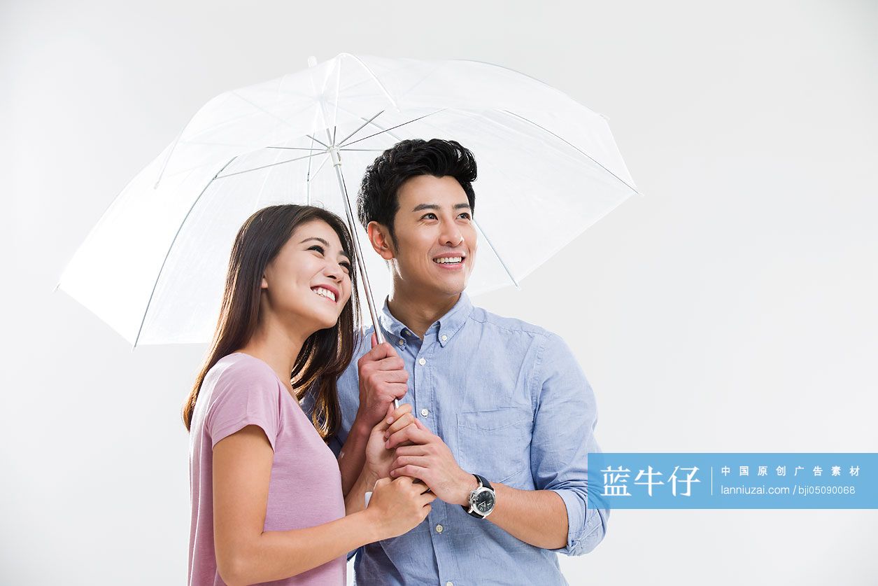 快乐的年轻情侣打着雨伞