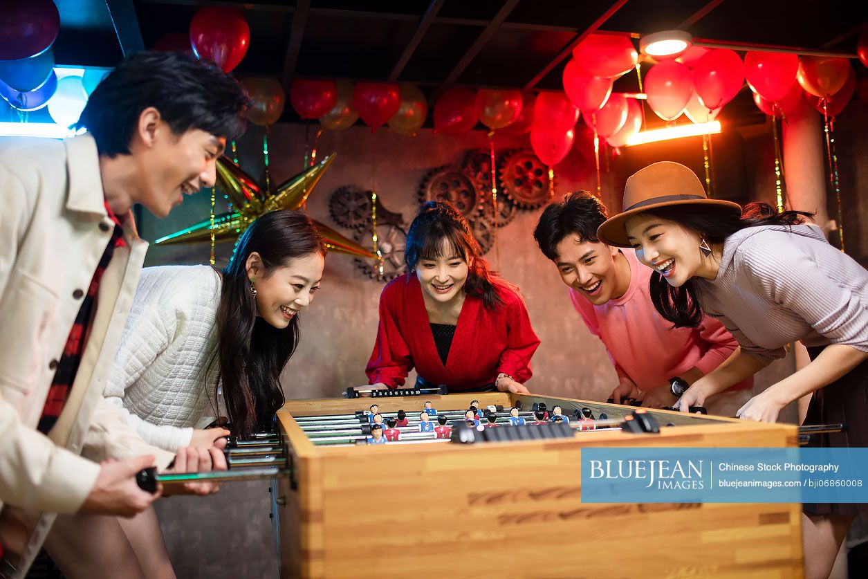 Happy young Chinese friends playing table football