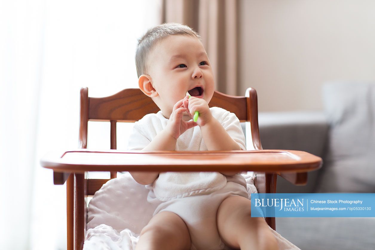 Cute Chinese baby boy sitting in high chair