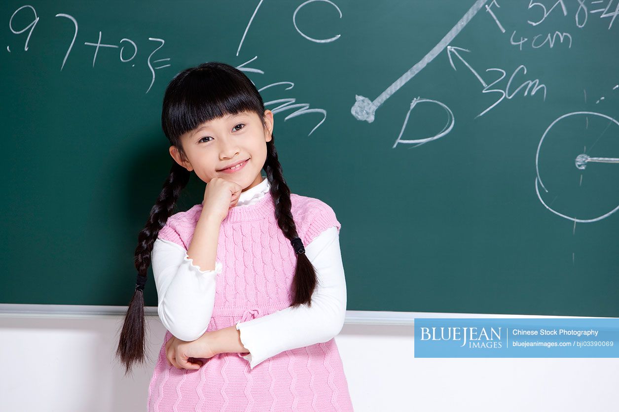 Cute little Chinese girl hand on chin in classroom