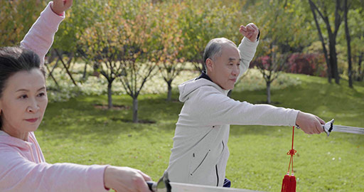 Cheerful senior Chinese adult practicing swords in the park,4K